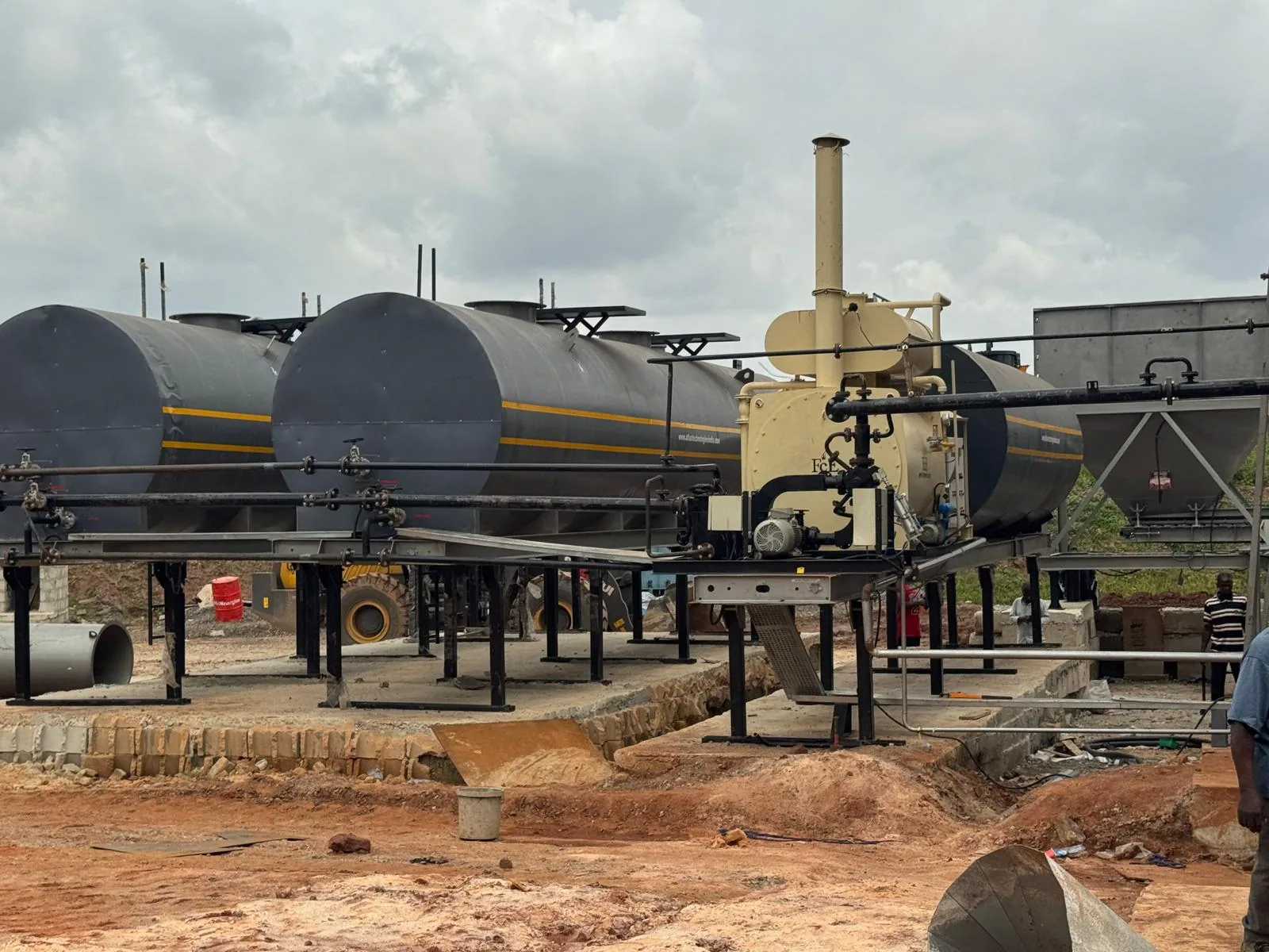 Horizontal bitumen storage tanks connected by heated pipework at the project plant yard.