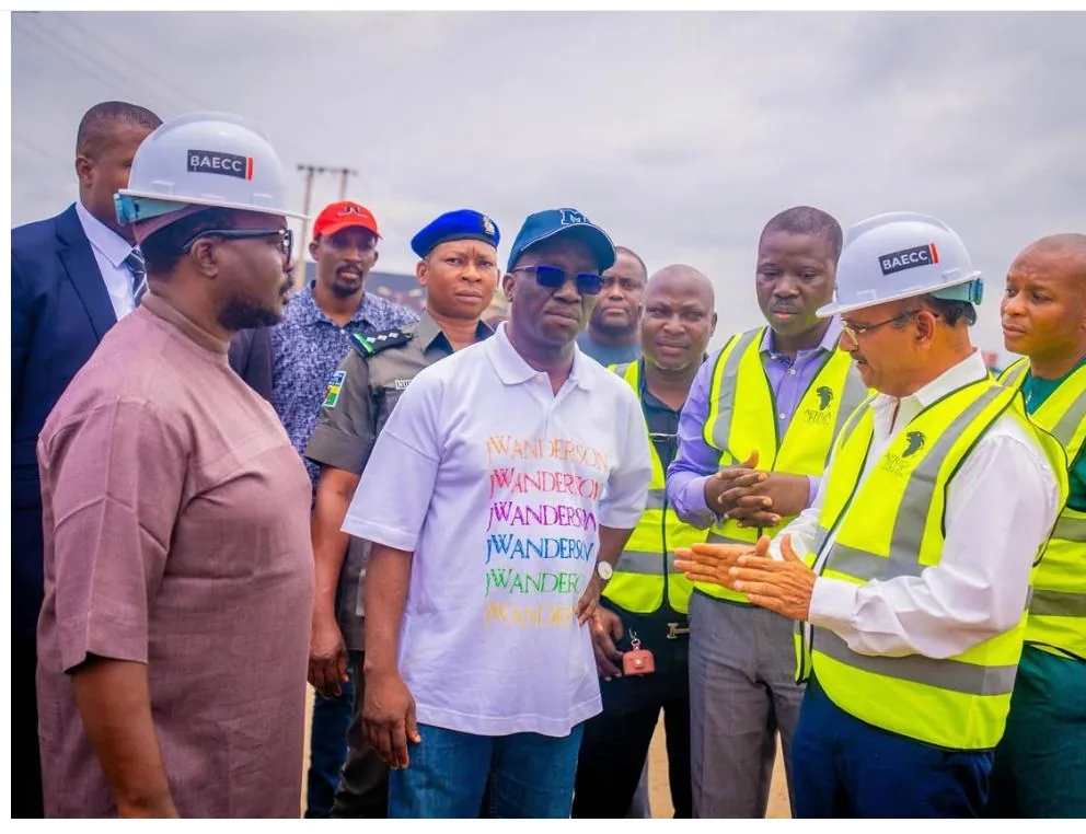 Project staff in BAECC helmets and high-visibility vests briefing visiting officials at the roadside.